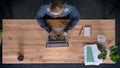 Top down view of man working in office in front of the laptop, being presented a big green gift-box.