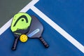 Top down view of paddles and balls for pickleball laid on a blue mat