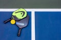 Top down view of paddles and balls for pickleball laid on a blue mat