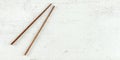 Top down view - pair of dark wood chopsticks on white board. Can be used as banner for asian / chinese food, space for text on Royalty Free Stock Photo