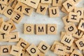 Top down view, pile of square wooden blocks with letters GMO stands for Genetically Modified Organism on white board