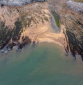 Top-down view of a rocky cove with sandy beach and turquoise ocean water Royalty Free Stock Photo