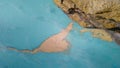 Top down view of sediments floating just below the surface of a turquoise volcanic lake. The camera moves upwards over