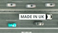 Trailer truck with MADE IN UK text driving along the road. British business related 3D rendering