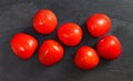 Top down view, seven mini tomatoes with drops of water on black stone desk