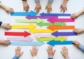 Top-down view of several hands pushing colored arrows in the same direction symbolizing teamwork alignment, coordination, and Royalty Free Stock Photo