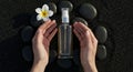 Spa Beauty: Hands Holding Cosmetic Spray Bottle with Plumeria and Stones Royalty Free Stock Photo