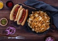 Top down view of a skillet filled with poutine fries and smokies on the side with toppings.