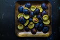 Top down view of sliced fresh blue plums on metal tray