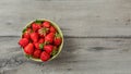 Top down view, small bowl with strawberries on gray wood desk. Space for text on right