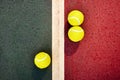 Three yellow tennis balls near the line of a green red concrete Royalty Free Stock Photo