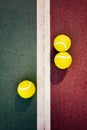 Three yellow tennis balls near the line of a green red concrete Royalty Free Stock Photo