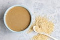 Top down view on traditional oriental sause tahini in a ceramic bowl and sesame seeds on light grey background. Close up. Blurred Royalty Free Stock Photo