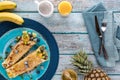 Top down view of tropical fruit crepes on a blue plate on a blue wooden table. Royalty Free Stock Photo