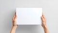 A top-down view of two hands holding a simple, plain white rectangular box against a light gray background, suggesting a product, Royalty Free Stock Photo