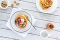 Top down view of two stacks of buttermilk pancakes with one being topped with berries and sliced banana. Royalty Free Stock Photo