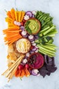 Top down view of a vegetable charcuterie platter with hummus dips against a light background. Royalty Free Stock Photo