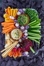 Top down view of a vegetable and hummus charcuterie platter surrounded by blue corn chips. Royalty Free Stock Photo