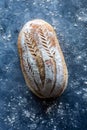 Top down view of a whole loaf of sourdough bread on a dark wooden table.