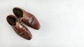 Top down view, worn classic dark brown brogue shoes on white board. Wide banner with space for text right