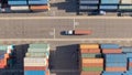 TOP DOWN: White truck transports a red freight container across the busy port. Royalty Free Stock Photo