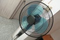 A top down wide angle view of a black floor standing electric fan with blue fan blades in a bedroom Royalty Free Stock Photo