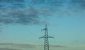 Top of electricity pylon and power lines in front of calm blue evening sky and clouds Royalty Free Stock Photo