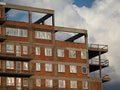 Top floors of a newly built red brick housing block with plastic windows covered with foil and gray concrete balconies Royalty Free Stock Photo