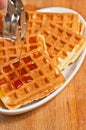 Pouring maple syrup on waffles