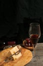 Rare wood dish with a wedge of cheese and cheese knife with glass of red wine Royalty Free Stock Photo
