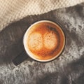 On top of the gray warm knit sweaters is a black mug with a fragrant strong coffee with cinnamon. A invigorating drink for