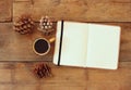 Top image of open notebook with blank pages, next to pine cones and cup of coffee over wooden table. retro filtered image Royalty Free Stock Photo