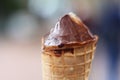Top of the licked melting chocolade ice cream waffle cone on the blurred background. The rest of the ice cream. Copy Space.