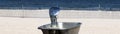 Top of old fashion water fountain with beach fence and water in background Royalty Free Stock Photo