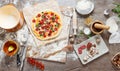 Top view cooking pizza with ingredients, tomatoes, salami and mushrooms on wooden tabletop Royalty Free Stock Photo