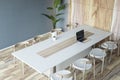 Top perspective view on stylish white conference table with modern laptop and chairs around on wooden floor and grey wall