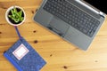 Top photography of a remote office while remote working with a wood background. Notebook in the desk. Writer freelance office