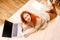 Top picture of a beautiful girl lying on the bed surfing the internet on the computer with headphones on. Royalty Free Stock Photo