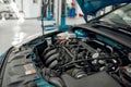 Car service. Close up of a car with open hood under under maintenance in auto repair shop Royalty Free Stock Photo