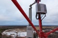 Top of red telecommunication tower with vertical panel antenna and remote radio unit, power and optic cables in winter Royalty Free Stock Photo