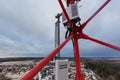 Top of red telecommunication tower with vertical panel antenna and remote radio unit, power and optic cables in winter day Royalty Free Stock Photo