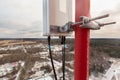 Top of red telecommunication tower with vertical panel antenna and remote radio unit, power and optic cables in winter day Royalty Free Stock Photo