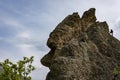 The top of a rocky mountain in the form of a head with a silhouette of a man with a camera against the cloudy sky on the Crimean Royalty Free Stock Photo