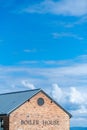 Top roof line of a boiler house building with blue sky and clouds Royalty Free Stock Photo
