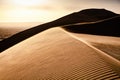 Top of a sand dune with sand dust blowing over the top. golden desert with sand dunes during sunrise. Erg Chebbi