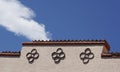 Top of Santa Fe theater front with circle patterns against blue sky and white cloud.