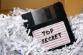 Top secret information on retro vintage floppy disk magnetic computer among shredder paper, thief information concept