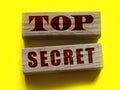 Top Secret words on wooden building blocks isolated on yellow. Marketing or yellow press scandal reveal concept