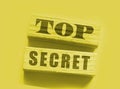 Top Secret words on wooden building blocks isolated on yellow. Marketing or yellow press scandal reveal concept