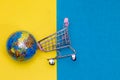 Top shot of cart with globe placed on blue and yellow background Royalty Free Stock Photo